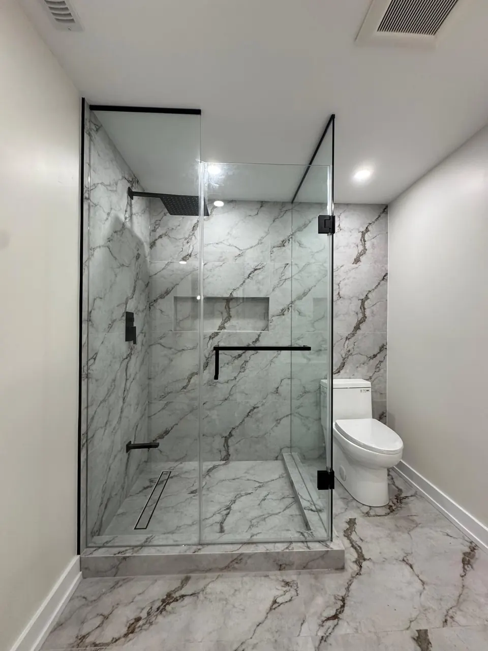 Corner glass shower with linear drain and black hardware