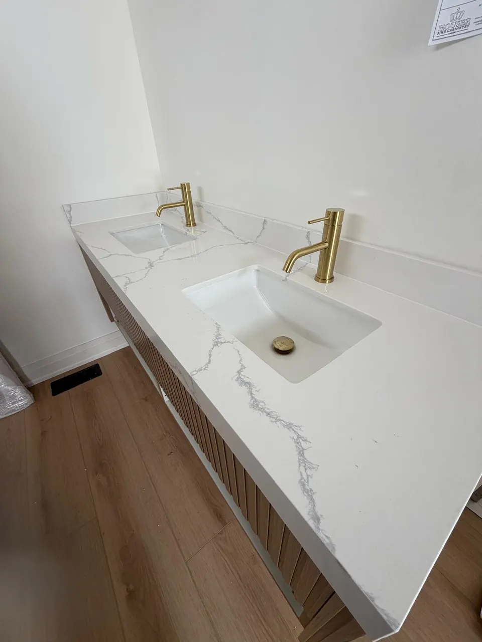 Double vanity with wood slat cabinet and gold faucets