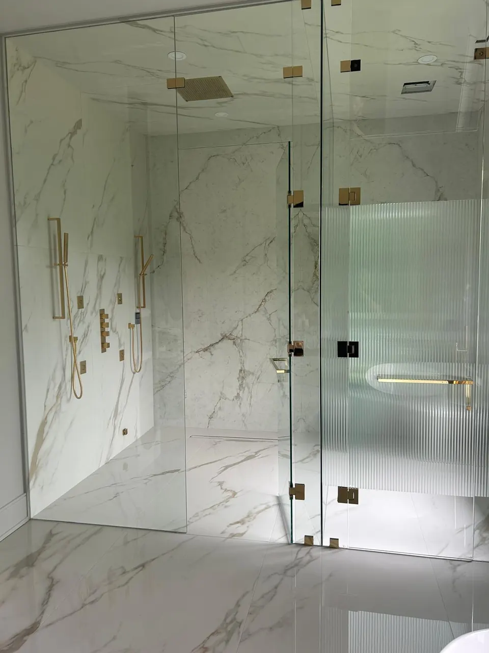 Frameless glass shower enclosure with gold hardware