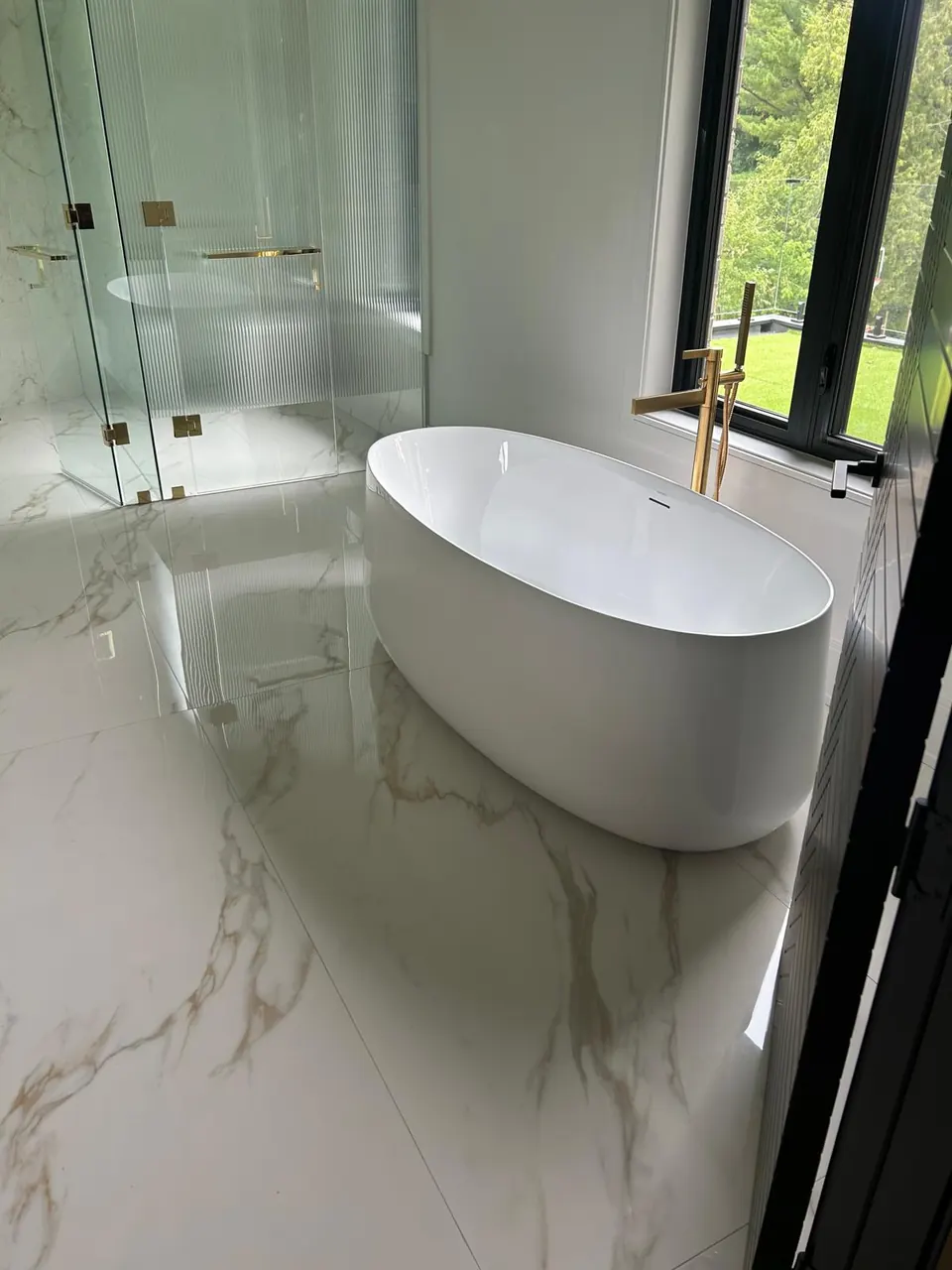 Freestanding soaker tub on marble-look porcelain floor