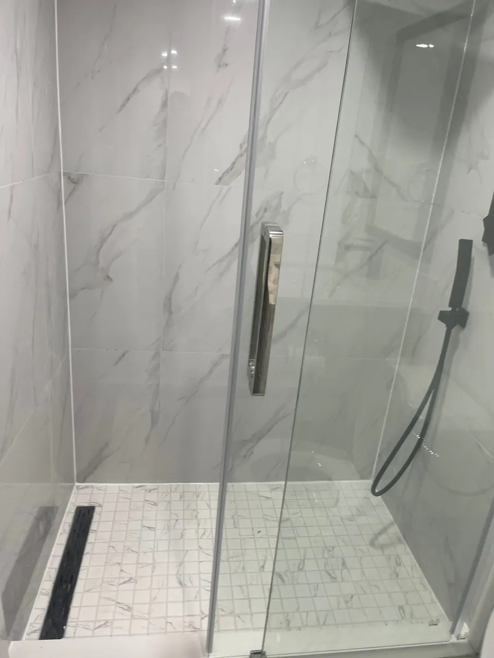 Walk-in shower with linear drain and mosaic tile base